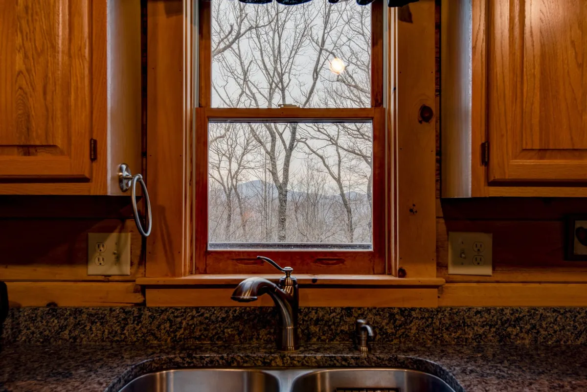 A kitchen window with a view, a farmhouse-style sink, and wooden cabinetry, suggesting a homely space to gather while appreciating the surrounding scenery. Ideal for prepping for picnics or meals before heading out to explore.