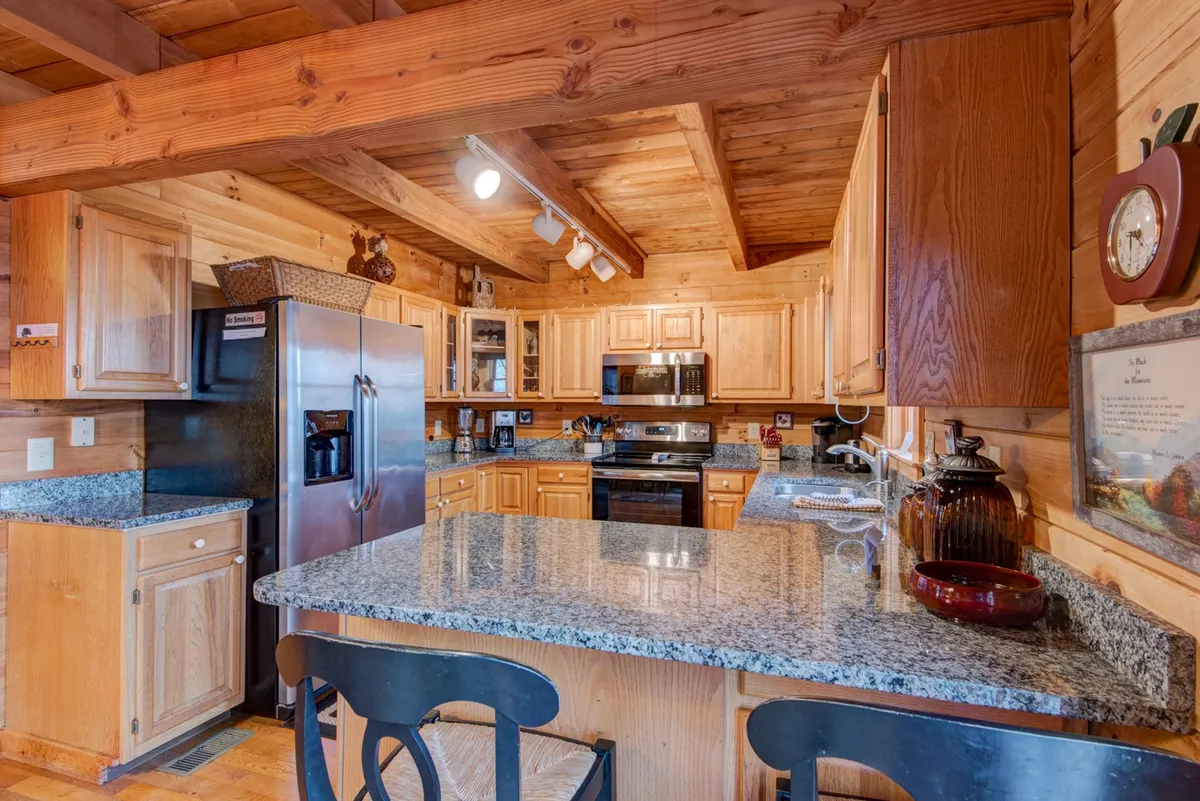 A modern, fully equipped kitchen with gleaming granite countertops, warm wooden cabinets, stainless steel appliances, and open shelving. The setup is ideal for both everyday cooking and special culinary adventures.